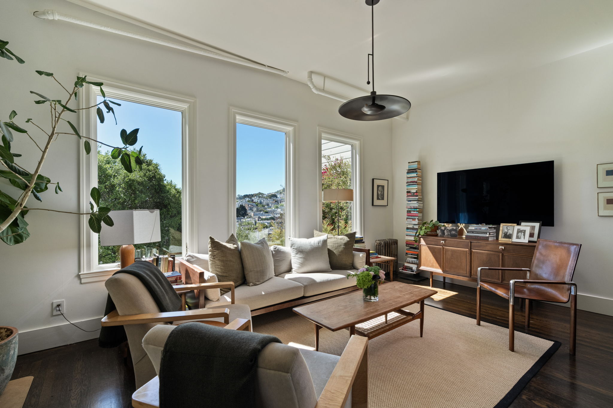 Sunlit living room with modern furnishings and hillside views in a San Francisco home